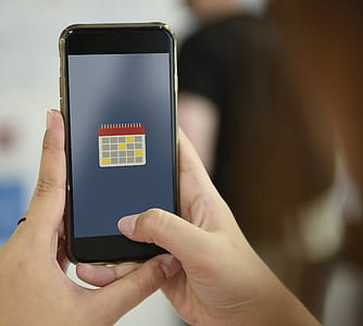 person holding iPhone displaying calendar thumbnail