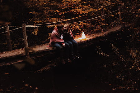 man and woman sitting on wooden bridge thumbnail