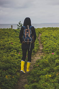 woman walking on dirty road in middle of flower field during daytime thumbnail