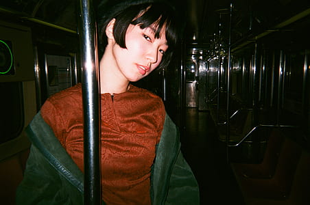 woman in black jacket and brown top leaning on silver post thumbnail