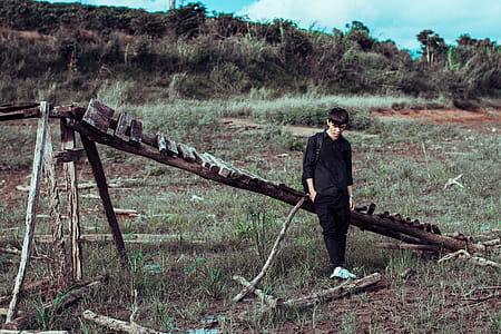Man Leaning on Wooden Bridge on Grass Field thumbnail