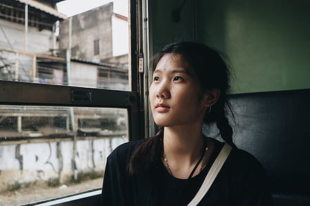 woman looking outside the window during day thumbnail