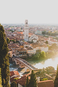 people walking on the bride over the river surrounded by houses and trees under daytime sky thumbnail