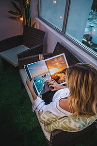 woman looking at wallpapers while sitting on brown wicker sofa by the window thumbnail
