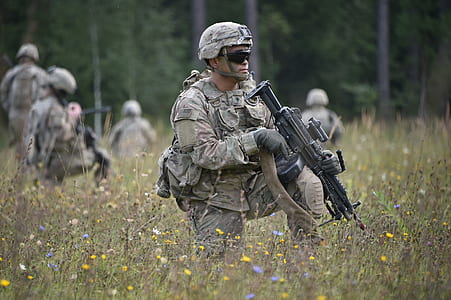 man holding assault rifle surrounded by yellow and blue flowers thumbnail