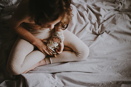 woman holding doll on bed thumbnail