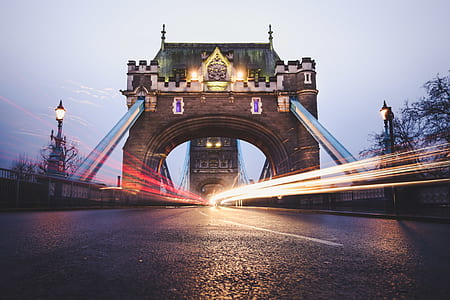 timelapse photography of vehicles passing thru the bridge near trees thumbnail