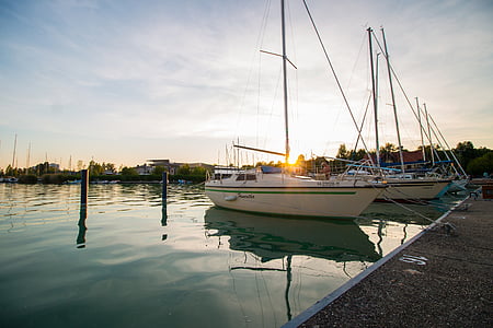 two inline white sailboats on calm body of water under white cloudy sky at daytime thumbnail