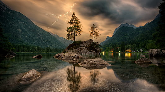 reflective photography of trees, rocks, and mountain with lightning strike in background thumbnail
