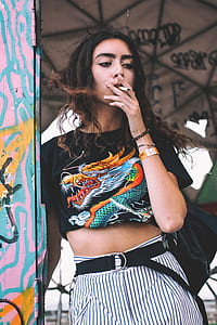 woman standing beside wall smoking thumbnail