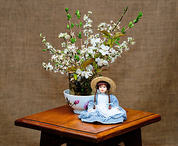 girl doll beside white flowers in vase thumbnail