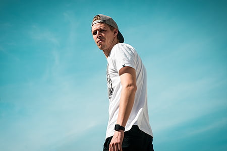 man in white shirt wearing cap under blue sky thumbnail