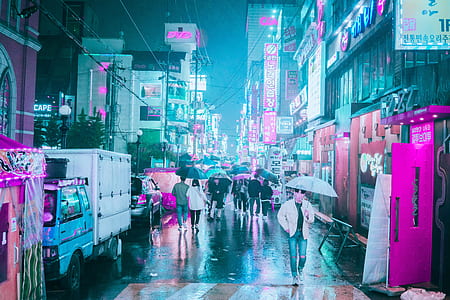 people holding umbrellas walking on street near buildings during night time thumbnail