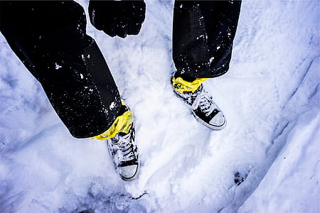 person wearing black pants and white shoes sitting on snow covered ground thumbnail