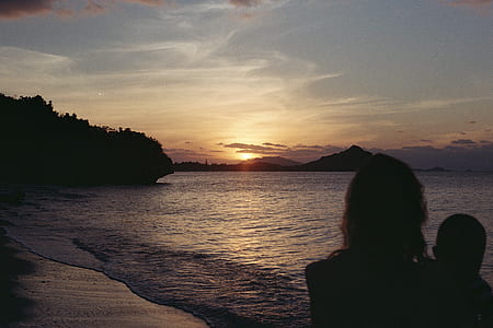 silhouette of two person on seashore during golden hour thumbnail