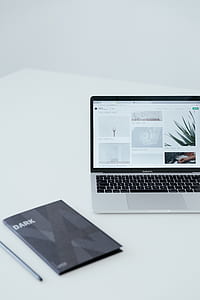 MacBook Pro turned on beside gray Dark notebook thumbnail