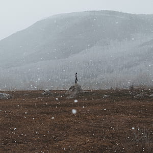 person standing on boulder near mountain thumbnail
