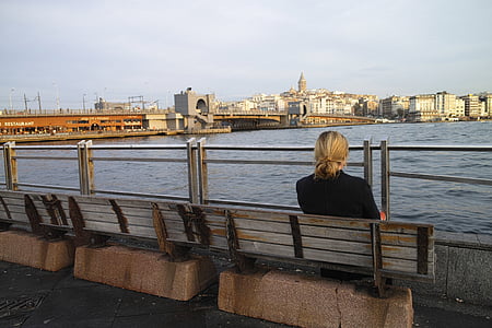 woman sitting on bench near body of water thumbnail