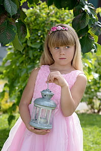 girl in dress holding lantern beside tree thumbnail