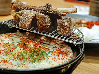 grilled meat on top of ceramic bowl with soup on table thumbnail