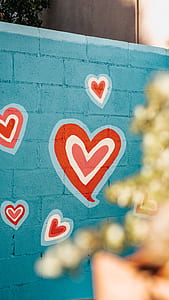 white and red heart painted on green concrete wall thumbnail