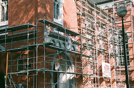 three men on top of scaffolding beside brick building thumbnail