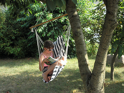 girl in pink tank top riding on portable hammock under the tree during daytome thumbnail