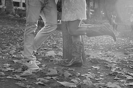 grayscale photo of two person standing beside tree thumbnail