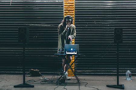 DJ holding microphone in front of MacBook on stage thumbnail