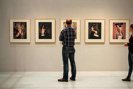 man standing in front of assorted paintings thumbnail