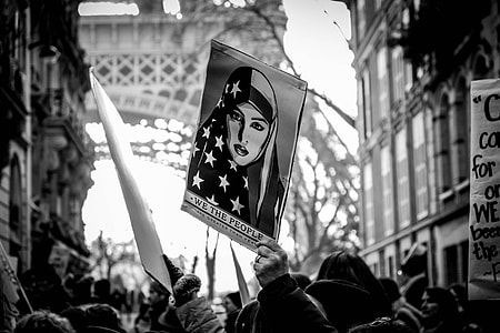 grayscale photography of person holding We The People banners thumbnail