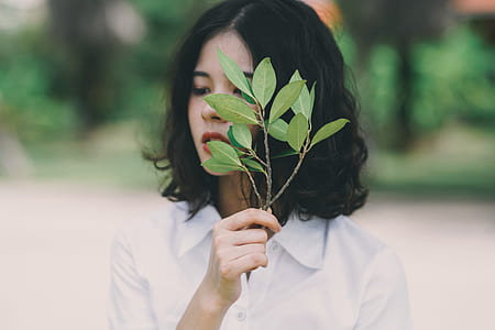 woman in white dress shirt holding green leaves thumbnail