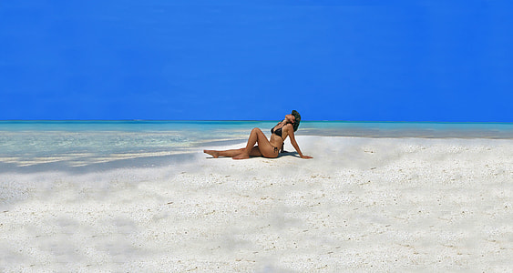 woman in black bikini on white beach sand near body of water thumbnail