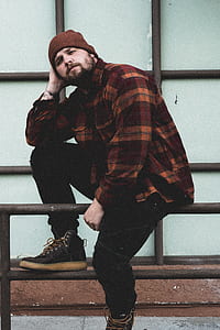man sitting on railings while holding his head thumbnail
