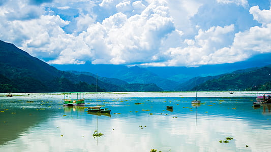 canoe floating on sea near mountain valley under cloudy sky thumbnail