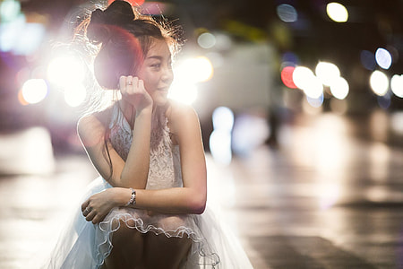 selective focus photograph of woman wearing white sleeveless dress sitting thumbnail