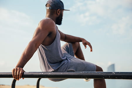A young African man wearing casuals relaxing on workout bars thumbnail