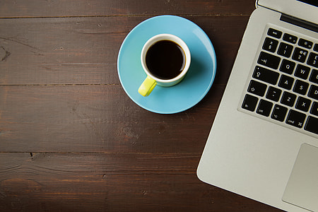 Overheard shot of a laptop computer and cup of coffee on a brown wood desk thumbnail