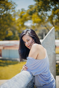 woman in gray off-shoulder top standing beside concrete stand thumbnail