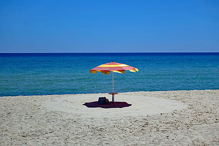 yellow and red patio umbrella on seashore thumbnail