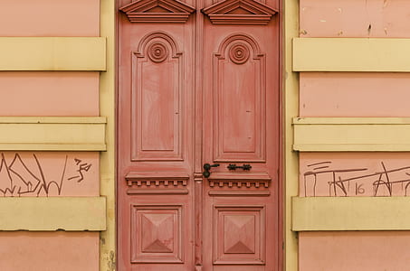 brown wooden door in between of yellow-and-pink painted wall thumbnail