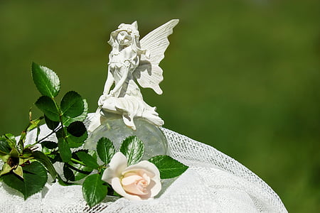 white fairy figurine on white cloth next to white rose thumbnail