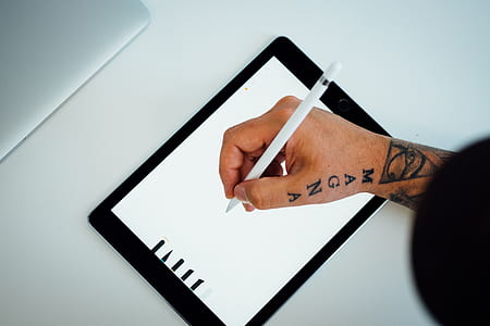 person writing on iPad using white stylus thumbnail