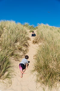 boy in gray top climbing a beige hill during daytime thumbnail