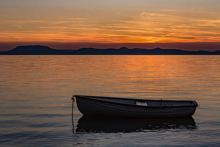 black boat on body of water during golden hour thumbnail