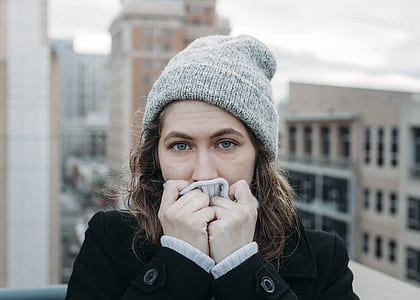 woman wearing black coat and gray knit cap covering mouth thumbnail