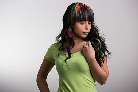 woman wearing green scoop-neck shirt and green lipstick holding hair thumbnail