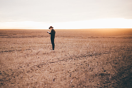 man wearing black suit standing on brown fields thumbnail