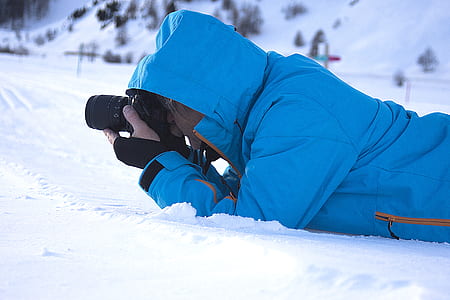 man lying on snowfield taking picture thumbnail
