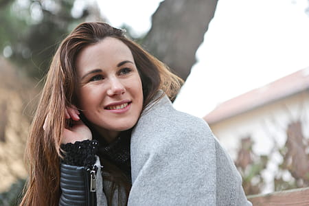 A young blonde woman in jacket smiling in the outdoors thumbnail